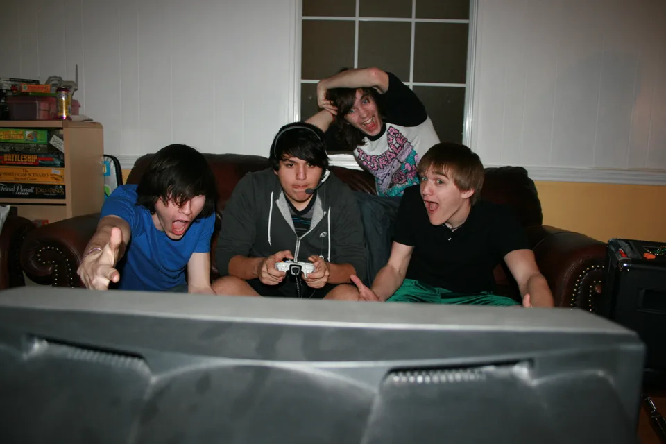 Four band members gathered on a couch around a game controller.