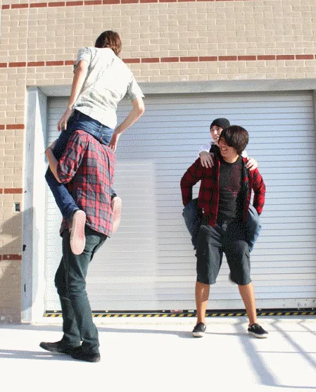 Animated sequence of band members riding on each other's shoulders outside a garage door.