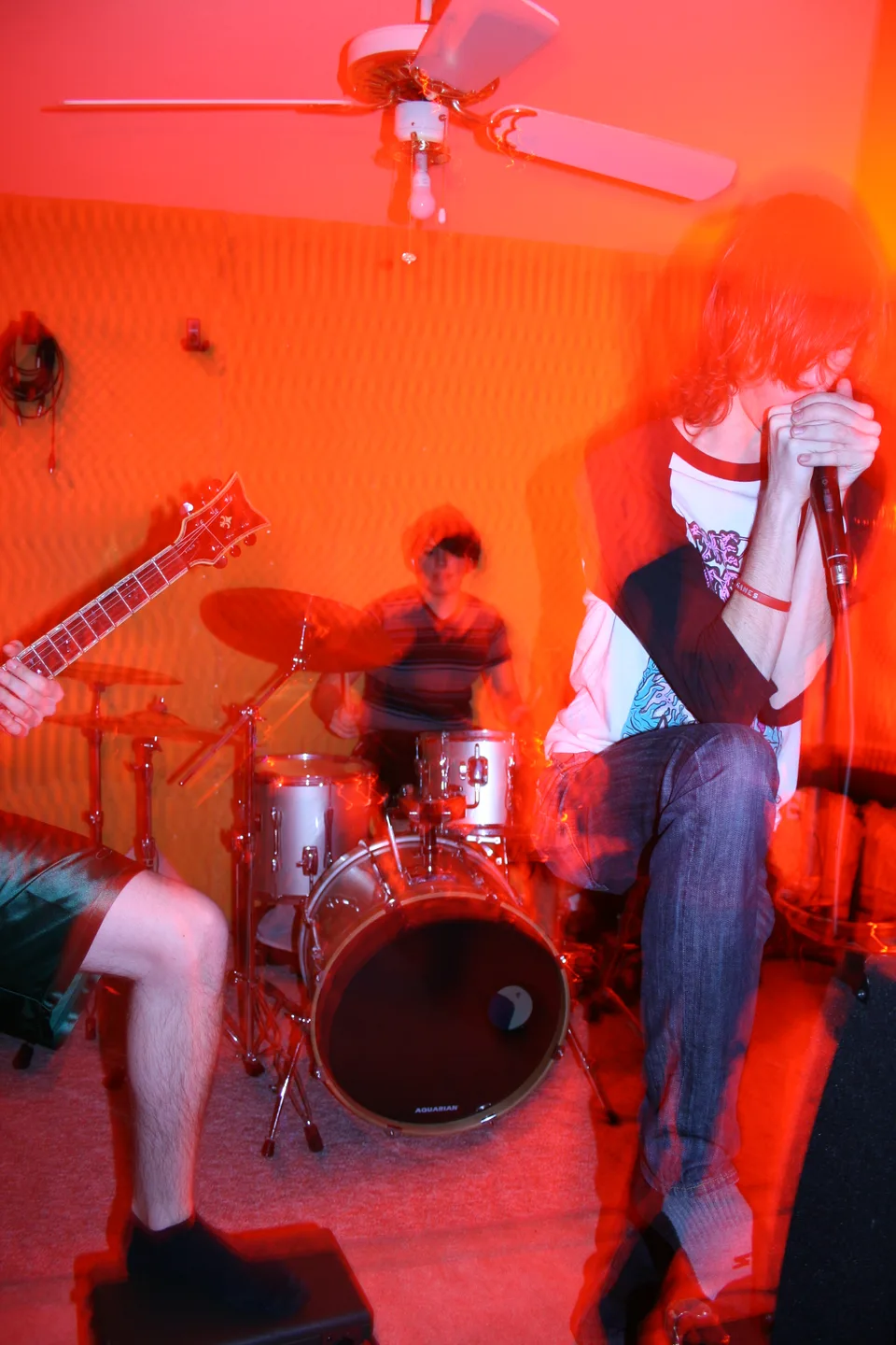 A vocalist and drummer rehearsing under orange light, with motion blur.