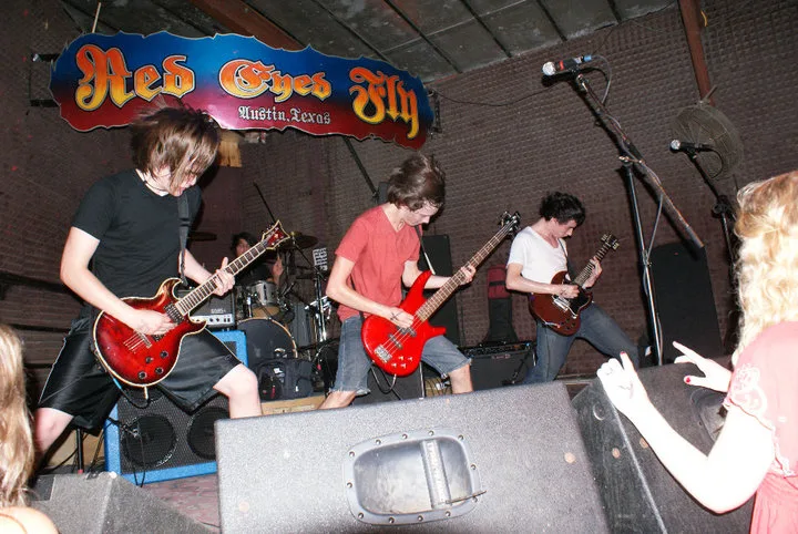 The band performing at Red Eyed Fly, photographed past stage monitors and audience members.
