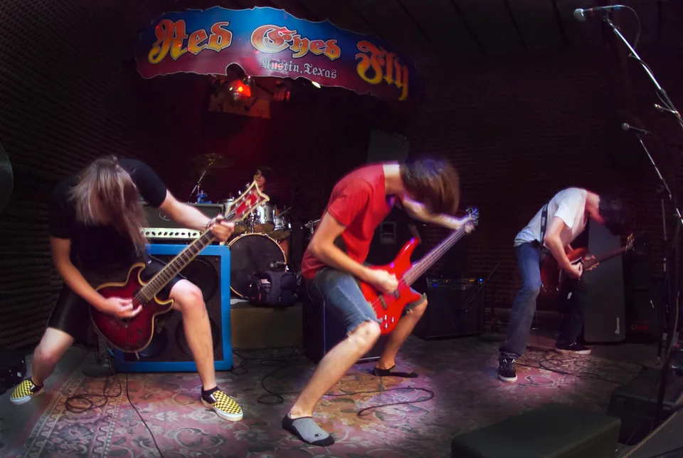 Three band members headbanging in front of the drummer at Red Eyed Fly.