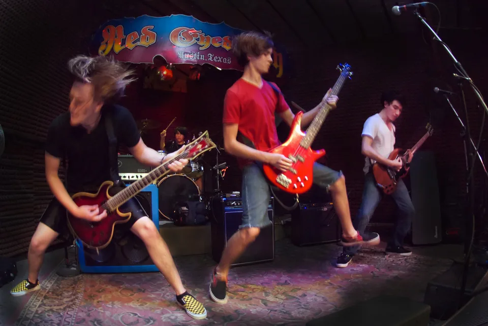 A bassist jumping between two guitarists while the band performs at Red Eyed Fly.